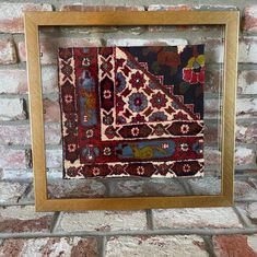 an old rug is hanging in front of a brick wall with a wooden frame on it