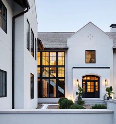 a white house with lots of windows and lights on the front door is lit up at night