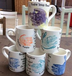 five coffee mugs with different handprinted designs on them sitting on a table