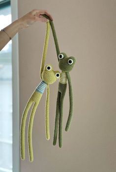 two crocheted stuffed animals hanging from strings in the shape of an octopus and squid