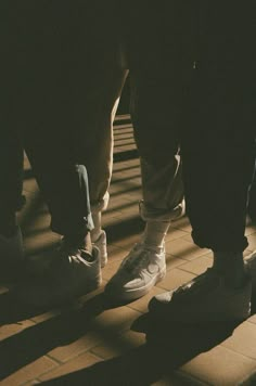 two people standing on the ground with their feet up and one person wearing white sneakers