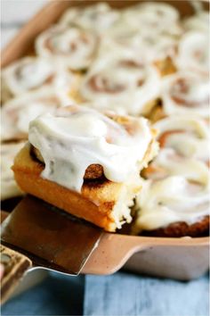 cinnamon rolls with icing sitting on top of a pan