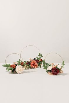 three hoop flower arrangements with leaves and flowers