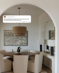 a dining room table with chairs and a vase on top of it in front of an archway