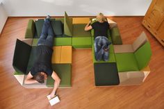 a man laying on top of a green and yellow couch next to a woman lying on the floor