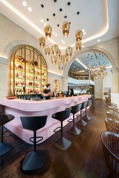 a bar with several stools in front of it and lights hanging from the ceiling