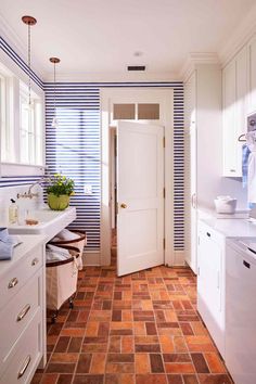 a kitchen with blue and white stripes on the walls, tile flooring and cabinets