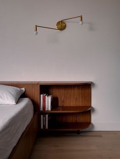 a bed with a book shelf next to it and a lamp on the wall above it