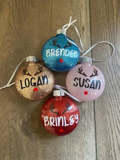 three ornaments with names on them sitting on a wooden floor