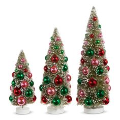 three small christmas trees with ornaments on them and one is green, red and pink