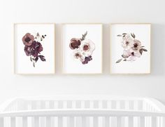 three floral prints hanging on the wall above a crib