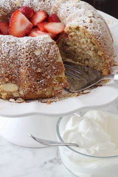 a white plate topped with a cake covered in powdered sugar and sliced strawberries