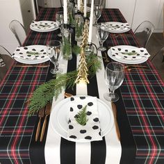 the table is set with black and white plaid napkins, silverware, greenery, and candles