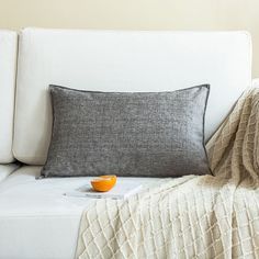 a white couch with a blanket and orange bowl on it