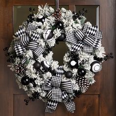 a wreath with black and white ornaments hanging on a door