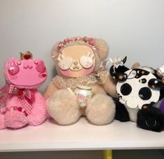 three stuffed animals sitting on top of a white shelf next to each other and one is wearing a tiara