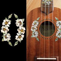 an ukulele with white flowers and green leaves on the fret, next to a pair of earrings