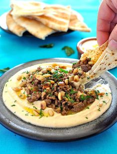 a person dipping some pita bread into a bowl