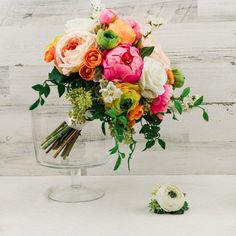 an arrangement of flowers in a glass vase on a white table with wood planks