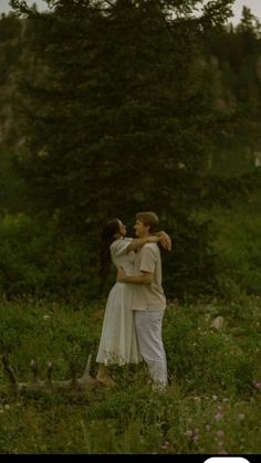 a man and woman are standing in the grass with their arms around each other as they hug