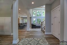 an open living room and kitchen area with hardwood floors, white walls, and large windows