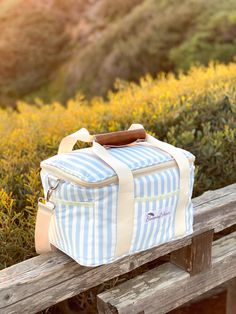 a blue and white striped bag sitting on top of a wooden bench