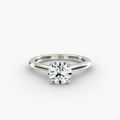 a white gold engagement ring with a round brilliant cut diamond in the center, on a plain surface