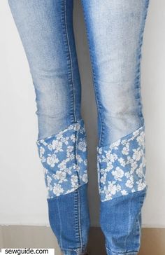 the legs of a woman wearing blue jeans with floral appliques on them and brown shoes