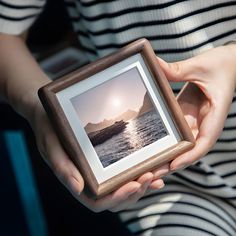 a person holding a small wooden frame with a photo on it in their hands,