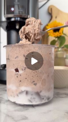 a cup filled with ice cream sitting on top of a counter next to a blender