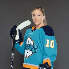 a female ice hockey player is posing for a photo with her stick and jersey on