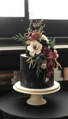 a black and white cake with red flowers on top is sitting on a table in front of a piano