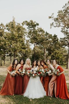 a group of women standing next to each other holding bouquets in front of trees