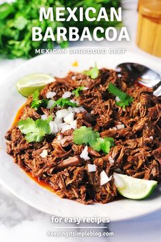 mexican beef barbacoa on a white plate with limes and cilantro