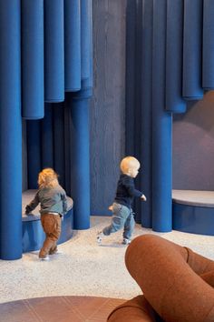 two small children are playing in front of some blue curtained walls and carpeting