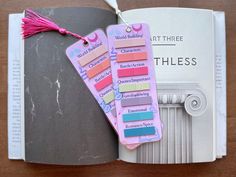 an open book with several different colored tags attached to the pages and tassels