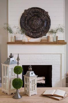 a living room with a fire place and books on the fireplace mantel, surrounded by greenery