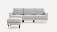 a white couch and ottoman sitting on top of a white floor next to each other