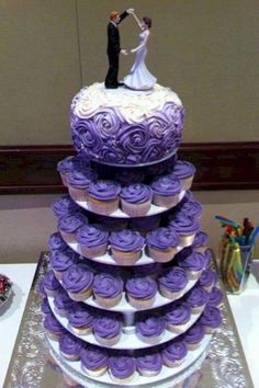 a purple wedding cake with cupcakes on top