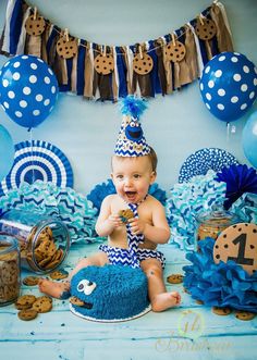 a baby is sitting on the floor with cookies and cake in front of him for his first birthday