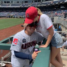 two women in baseball uniforms leaning on the bleachers at a ball game,