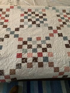 a bed with a quilt on top of it next to a person's feet