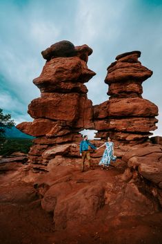 a man and woman standing on top of a rock formation