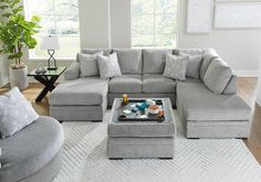 a living room with gray couches and white rugs on the hardwood flooring