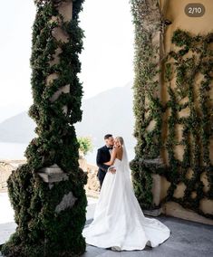 a bride and groom standing in front of an archway with ivy growing all over it