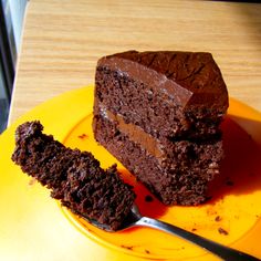 a piece of chocolate cake sitting on top of a yellow plate next to a fork