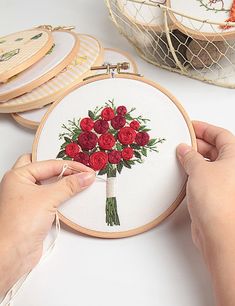 a person is stitching flowers on a piece of fabric in front of some baskets