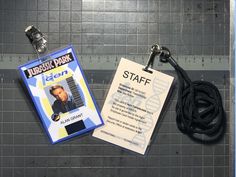 an id badge and lanyard attached to a wall next to a measuring tape with a name tag on it