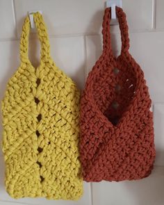 two crocheted purses hanging on the wall next to each other in different colors