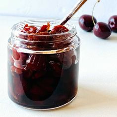 a jar filled with cherries sitting on top of a table